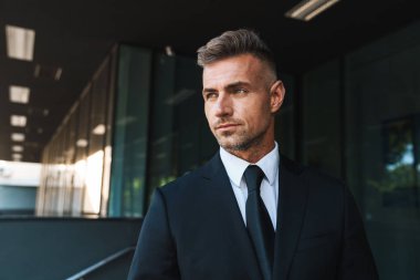 Gri saçlı yakışıklı iş adamı iş merkezi yakınındaki sokakta açık havada.