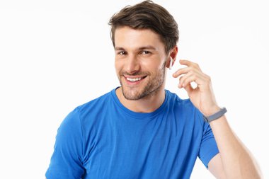 Rahat t-shirt neşeli adam Fotoğraf closeup gülümseyerek ve kablosuz earpods giyerken kamera bakarak