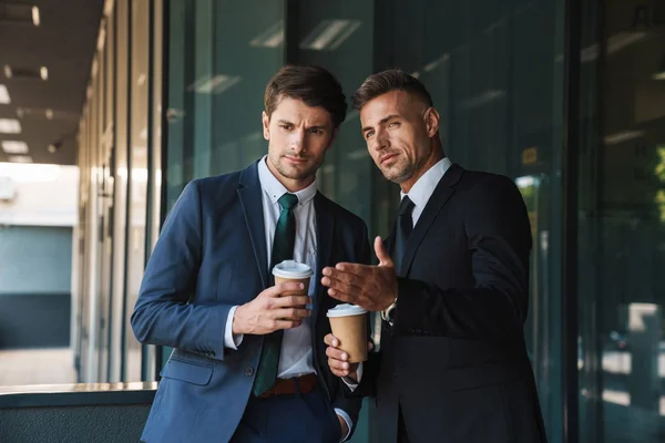 Koledzy przystojni biznesmeni na zewnątrz na ulicy w pobliżu centrum biznesowego rozmawiają ze sobą kawę pitną. — Zdjęcie stockowe
