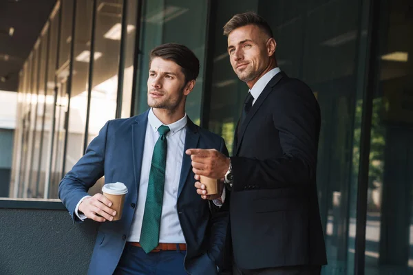 Chers collègues beaux hommes d'affaires à l'extérieur dans la rue près du centre d'affaires en train de se parler en buvant du café . — Photo