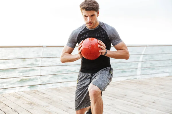 Stark allvarlig koncentrerad ung sport man utomhus göra övningar med bollen. — Stockfoto