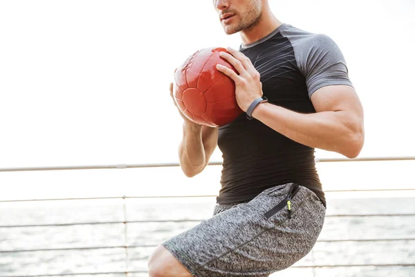 Forte jovem desportista ao ar livre fazer exercícios com bola . — Fotografia de Stock