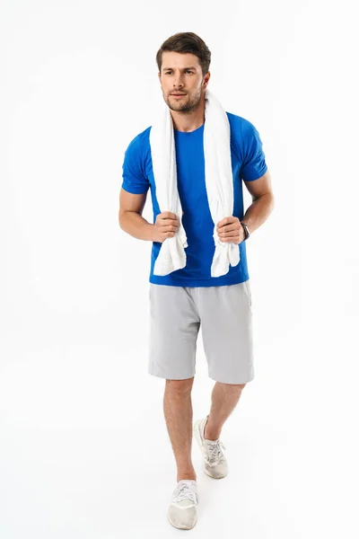 Bello giovane sport fitness uomo in piedi isolato su parete bianca sfondo tenendo asciugamano . — Foto Stock