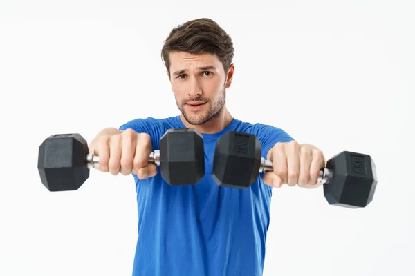 Guapo joven deportista de fitness de pie aislado sobre fondo de pared blanca hacer ejercicios duros con pesas . — Foto de Stock