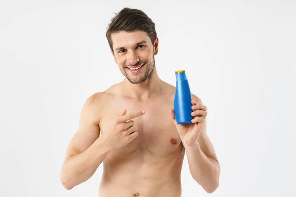 Foto de primer plano de caucásico hombre desnudo sonriendo y sosteniendo champú —  Fotos de Stock