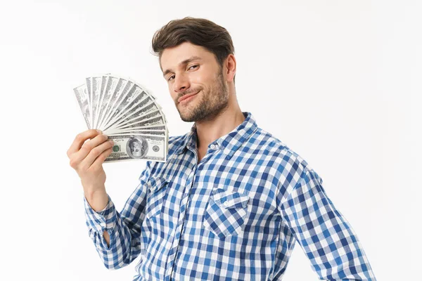 Handsome bearded unshaved pleased man dressed in casual shirt posing isolated over white wall background holding money. — Stock Photo, Image