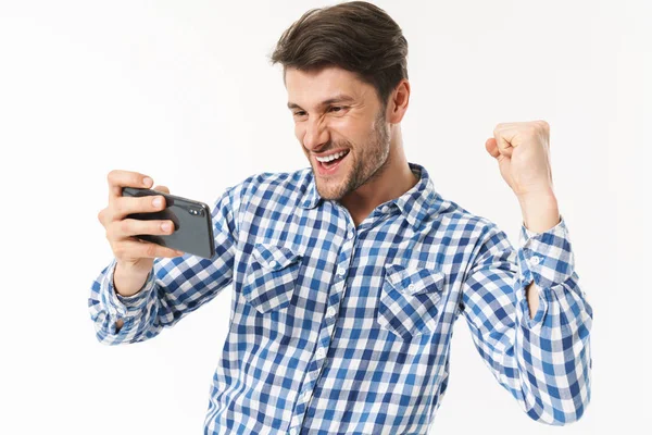 Foto de un hombre exitoso con camisa casual jugando videojuego en el teléfono celular y apretando el puño — Foto de Stock