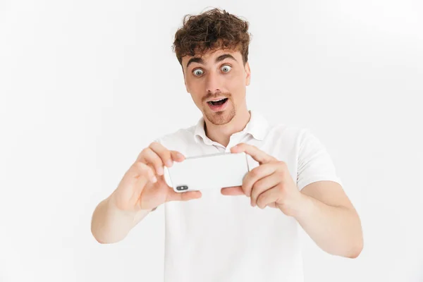 Imagen de primer plano del hombre sorprendido en camiseta casual sosteniendo smartph — Foto de Stock