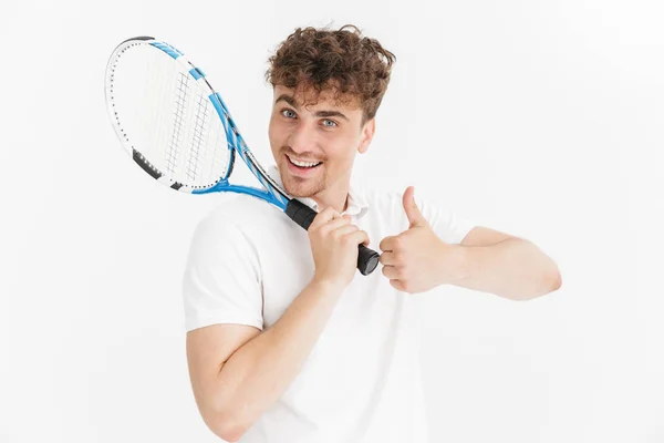 Φωτογραφικά πλάνα του θετικού άντρα στο μπλουζάκι που δείχνει τον αντίχειρά του και κρατώντας μια ρακέτα παίζοντας τένις — Φωτογραφία Αρχείου