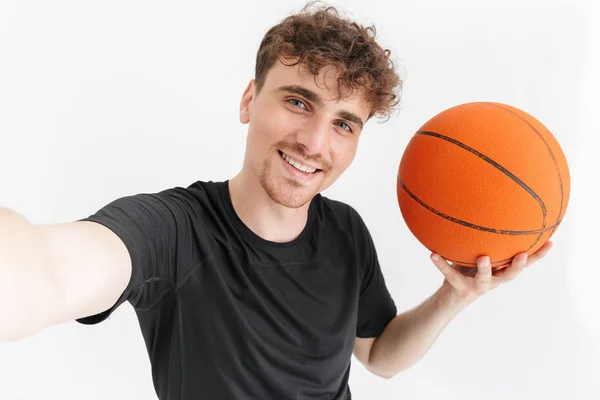 Foto close-up de jovem musculoso em t-shirt sorrindo e tomando selfie enquanto segurando basquete — Fotografia de Stock