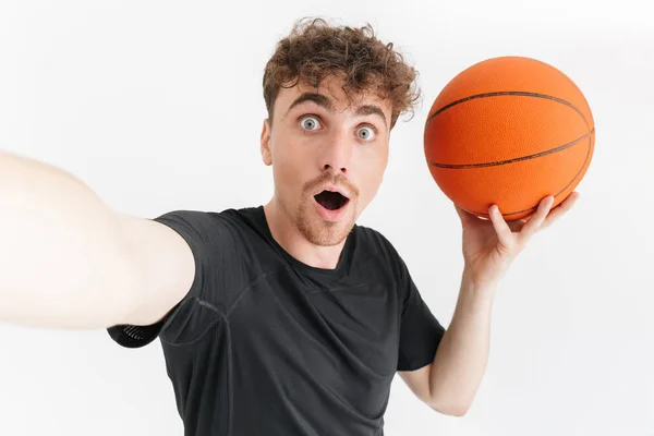 Foto primo piano di eccitato giovane uomo in t-shirt chiedendo e prendendo selfie mentre tiene il basket — Foto Stock