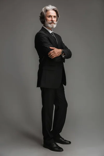 Ganzes Bild eines erwachsenen kaukasischen Geschäftsmannes im formalen schwarzen Anzug, der mit verschränkten Armen vor der Kamera steht — Stockfoto
