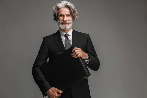 Bild eines glücklichen erwachsenen Geschäftsmannes im formalen schwarzen Anzug, der in die Kamera lächelt und Aktentasche hält — Stockfoto