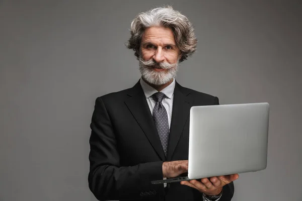 Image of unshaven adult businessman wearing formal black suit holding silver laptop — Stock Photo, Image