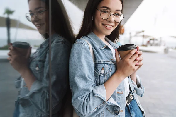 Image of joyful smiling teenage girl holding paper cup of takeaw