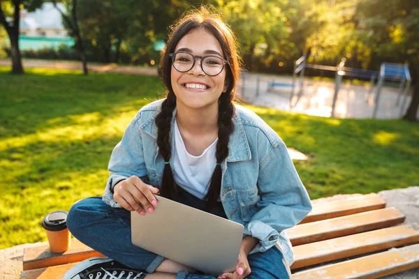 Alegre estudiante chica sentado en un banco en el parque — Foto de Stock