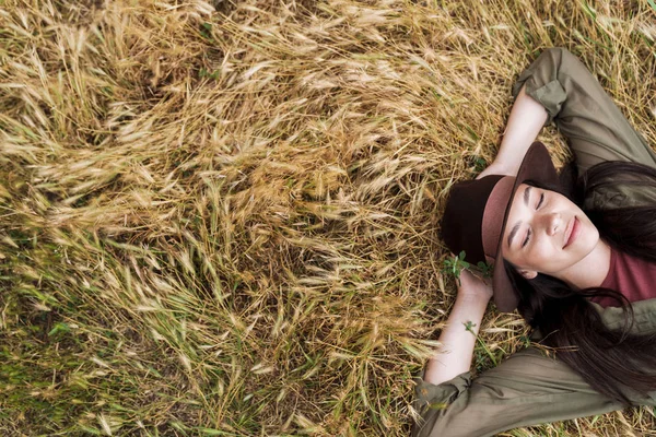 Foto de la parte superior de la mujer bonita relajada acostada y descansando con los ojos cerrados en el campo al aire libre —  Fotos de Stock