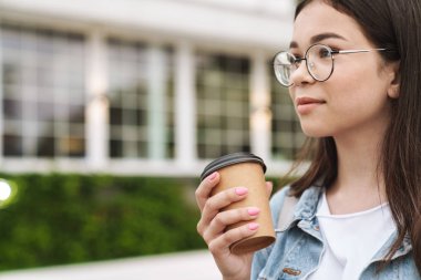 Memnun genç güzel kadın öğrenci yeşil doğa parkı kahve içme açık havada yürüyüş.