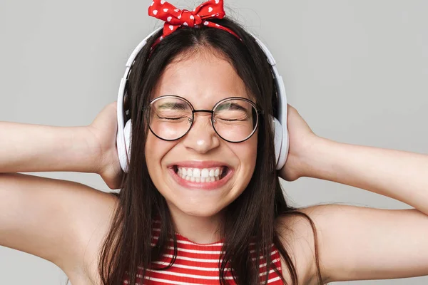 Emocionado joven adolescente disgustado vestido con brillante camiseta roja escuchar música aislada sobre fondo gris de la pared . —  Fotos de Stock