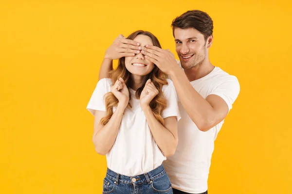 Foto av ung man leende och täcker kvinnans ögon stående vara — Stockfoto