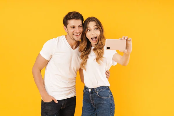 Ritratto di coppia stupita uomo e donna in magliette basiche che si rallegrano mentre scattano foto di selfie insieme su smartphone — Foto Stock