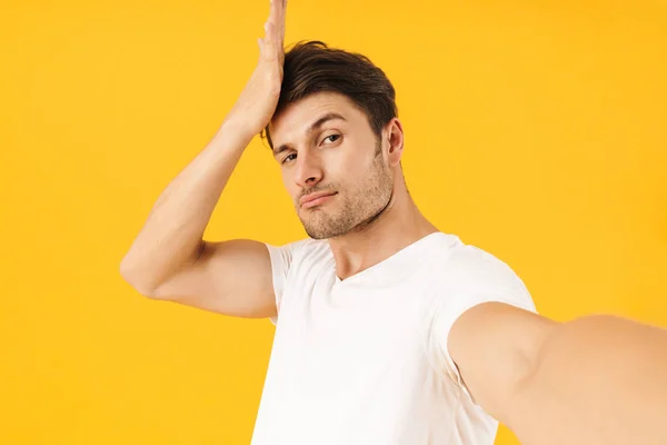 Foto de homem morena em camiseta básica posando na câmera com arr — Fotografia de Stock