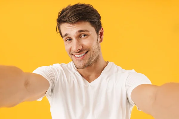 Foto de hombre alegre en camiseta básica sonriendo a la cámara mientras t — Foto de Stock