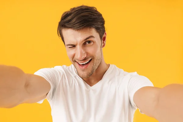 Foto van optimistische man in Basic t-shirt winking en glimlachend op — Stockfoto