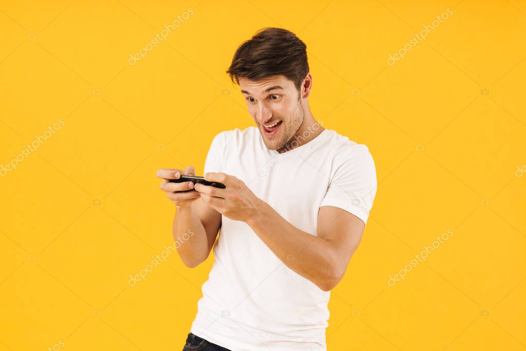 Photo of excited man in basic t-shirt rejoicing while playing vi
