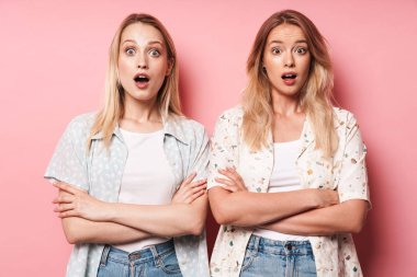 Duygusal şok güzel sarışınlar kadın arkadaşlar pembe duvar arka plan üzerinde izole poz.