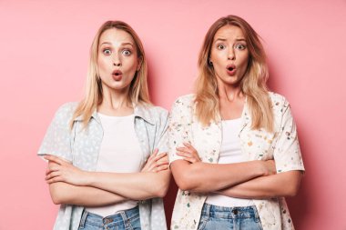 Sürpriz şok güzel sarışınlar kadın arkadaşlar pembe duvar arka plan üzerinde izole poz.