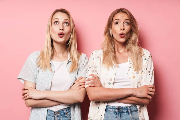 Sorprendido impactado guapas rubias mujeres amigas posando aisladas sobre fondo de pared rosa . —  Fotos de Stock