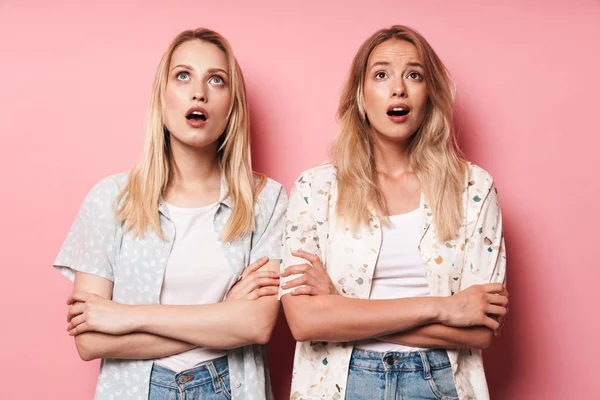 Emotional shocked pretty blondes women friends posing isolated over pink wall background. — Stock Photo, Image