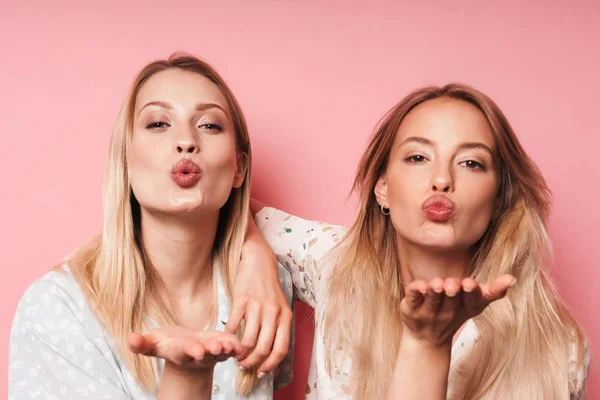 Piacevole graziosa bionde donne amiche posa isolato su rosa parete sfondo soffiando baci . — Foto Stock