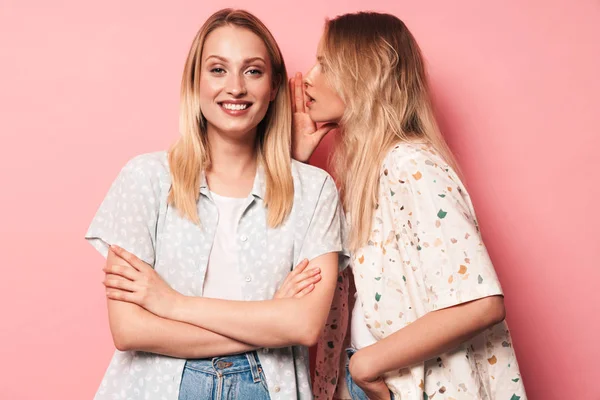 Приятно улыбаются красивые блондинки женщины друзья позируют изолированные на фоне розовой стены разговаривая друг с другом сплетничая . — стоковое фото