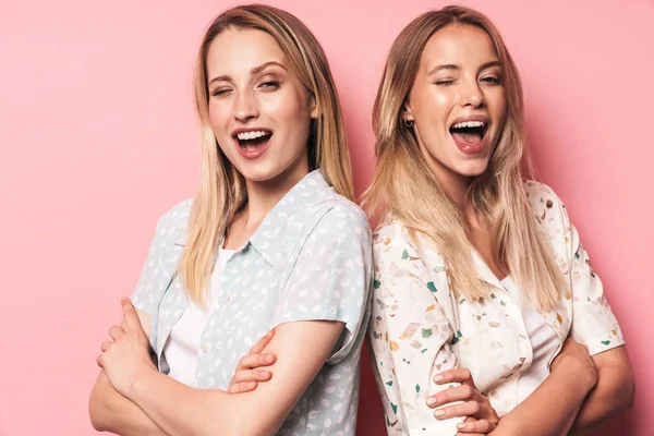 Bonito belas loiras felizes mulheres amigos posando isolado sobre fundo de parede rosa . — Fotografia de Stock