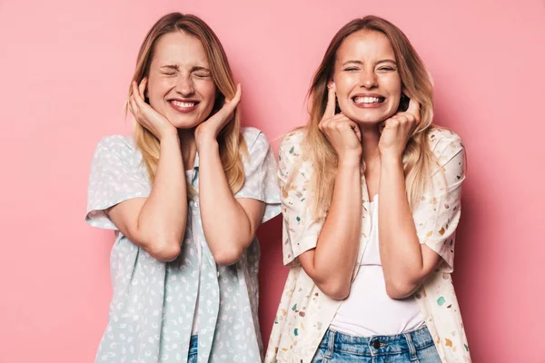 Chicas disgustadas mujeres amigas hermanas aisladas sobre fondo de pared rosa que cubre las orejas debido a ruidoso . — Foto de Stock