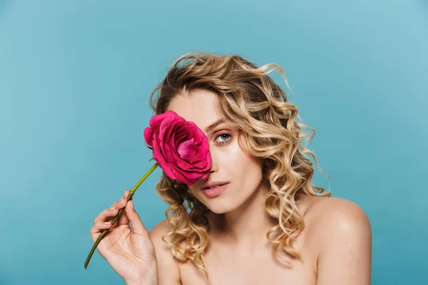 Image of pretty half-naked woman with curly hair looking at camera while holding pink flower — Stock Photo, Image