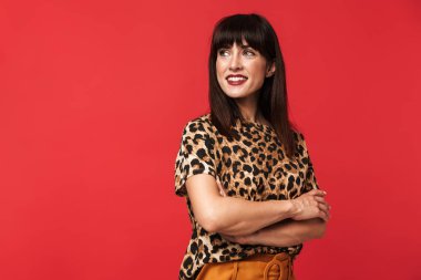 Güzel genç kadın kırmızı arka plan üzerinde izole poz hayvan baskılı gömlek giymiş.