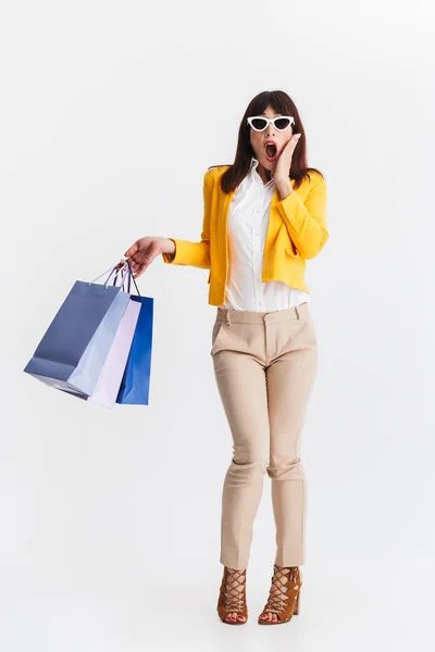 Chockad ung affärskvinna som utgör isolerad över vit bakgrund hålla shoppingväskor. — Stockfoto