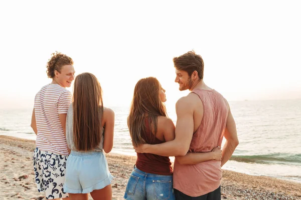 Vista trasera de un grupo de personas de pie en la playa — Foto de Stock