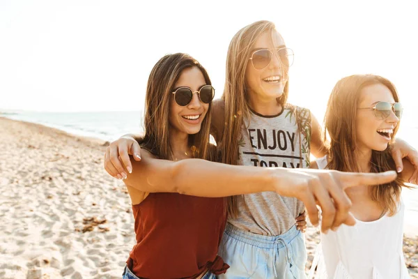 Drie vrolijke meiden die langs het strand wandelen, plezier hebben — Stockfoto