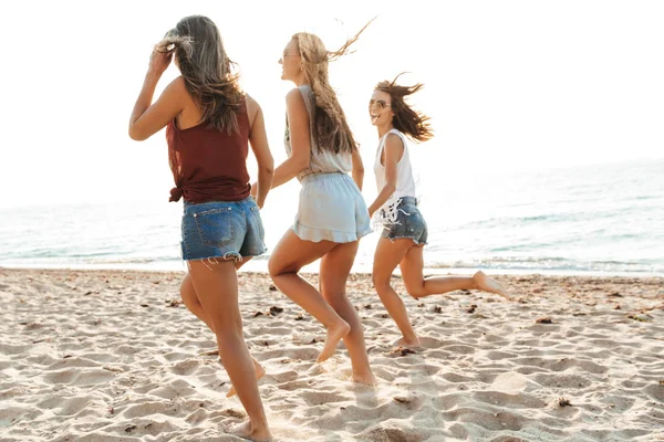 Trois filles gaies marchant le long de la plage, s'amusant — Photo