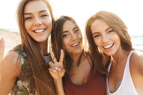 Drei fröhliche Mädchen, die am Strand spazieren gehen und Spaß haben — Stockfoto