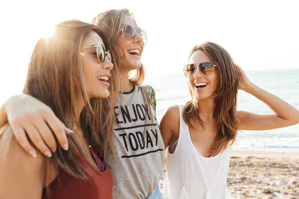 Tre ragazze allegre che camminano lungo la spiaggia, divertendosi — Foto Stock