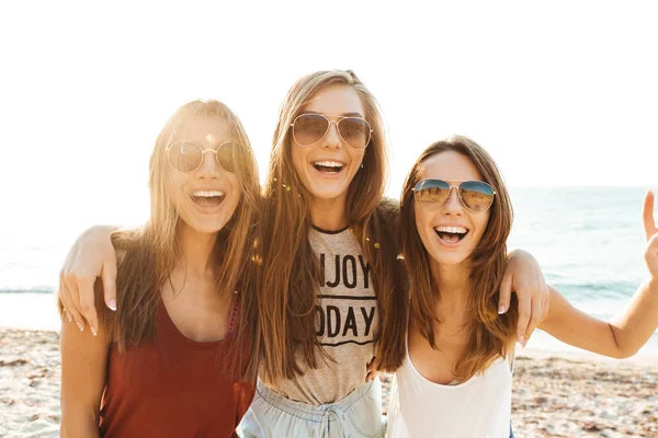 Drei fröhliche Mädchen, die am Strand spazieren gehen und Spaß haben — Stockfoto