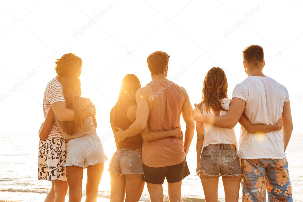 Back view of a group of people standing at the beach