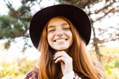 Neşeli gülümseyen mutlu genç öğrenci kızıl saçlı kız sonbahar parkta yürüyüş.