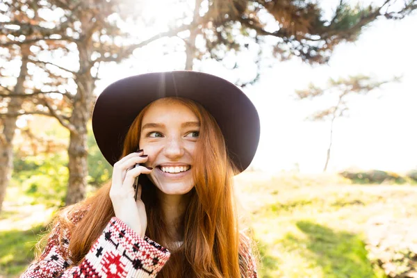 Feliz cutie complacido joven estudiante pelirroja en el parque de otoño utilizando el teléfono móvil . — Foto de Stock