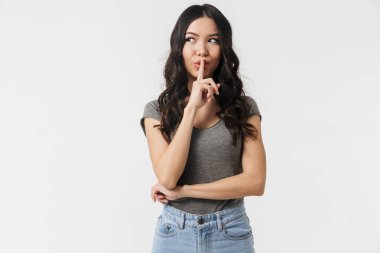 Beyaz duvar arka plan üzerinde sessizlik jest gösteren izole poz genç kadın.